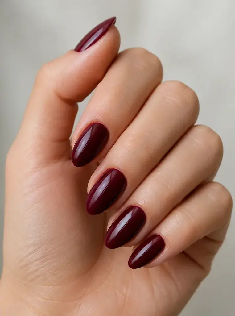 Before and after of natural nails changed to burgundy almond nails, after