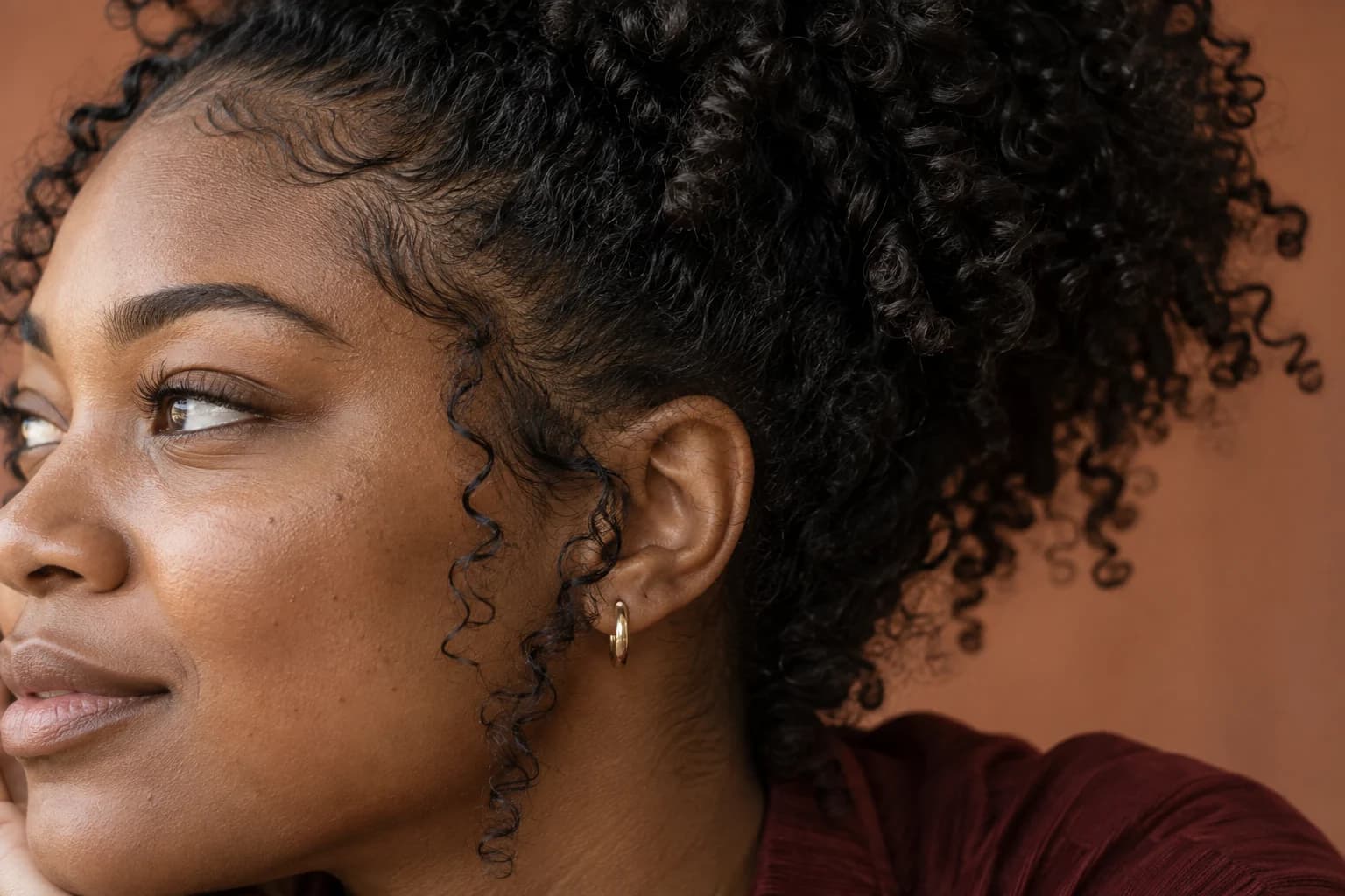 Close-up of natural coils, baby hairs at the temple and a loose face-framing curl