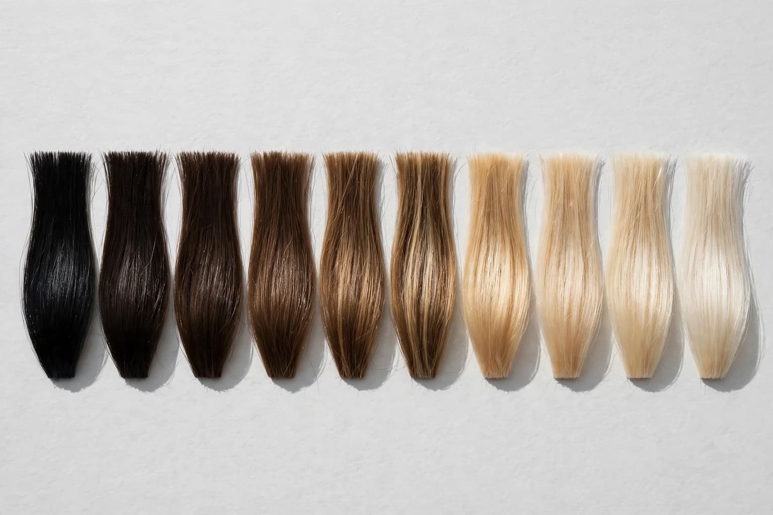 A professional hair color level chart from level 1 black to level 10 platinum blonde, with hair swatches arranged in a row from darkest to lightest